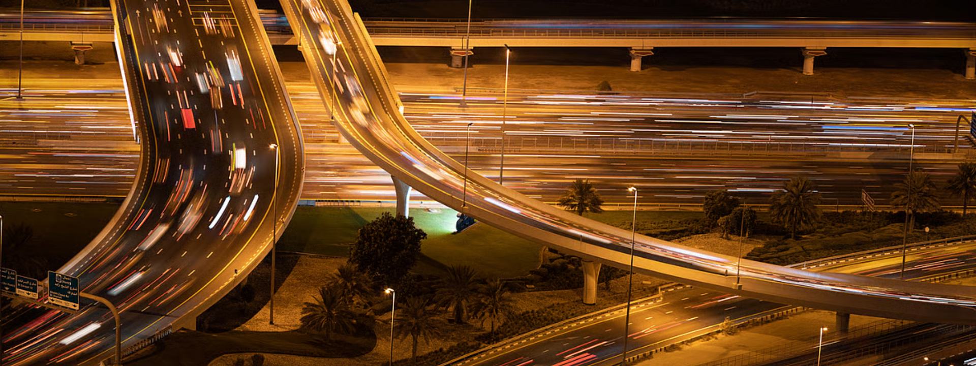 Nighttime highway interchange with long-exposure light trails from moving traffic