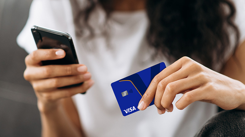 A person holding a phone and a credit card