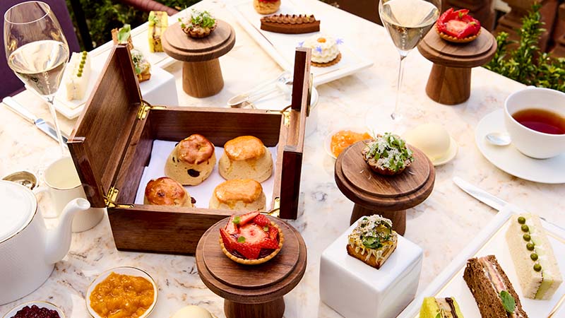 Elegant afternoon tea spread with pastries, sandwiches, scones, and tea served on a marble table