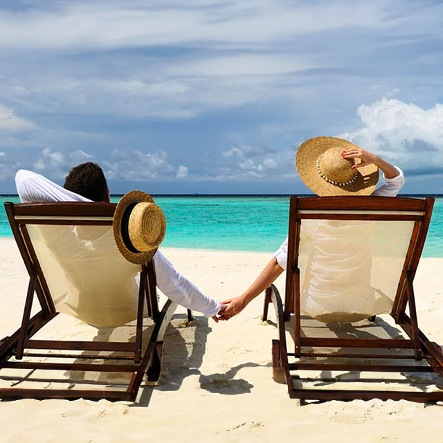 People relaxing in sun loungers on the beach by the ocean
