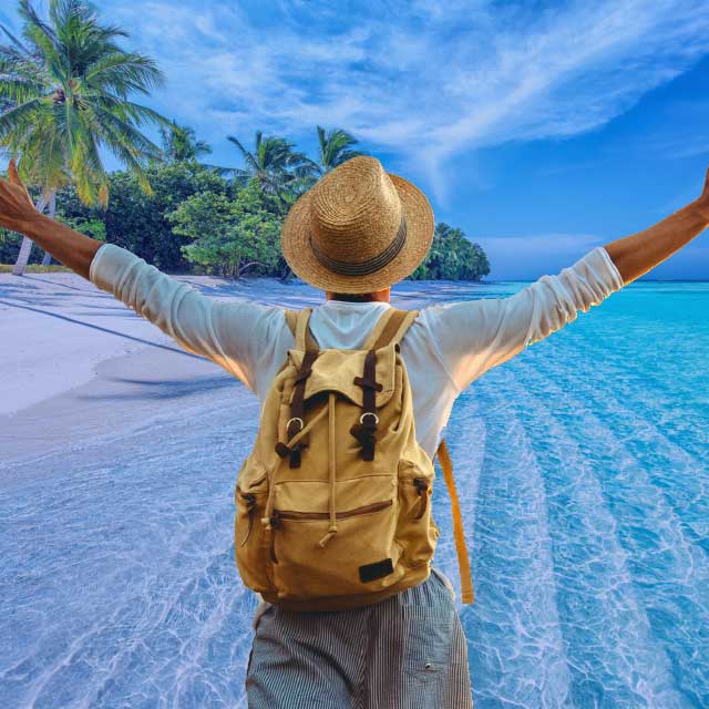 Person with a backpack and a straw hat by the ocean