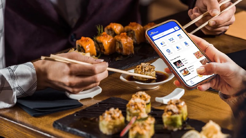 People enjoying sushi at a restaurant while using a food delivery app on a smartphone