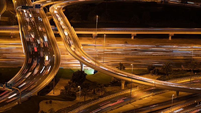 Nighttime highway interchange with long-exposure light trails from moving traffic